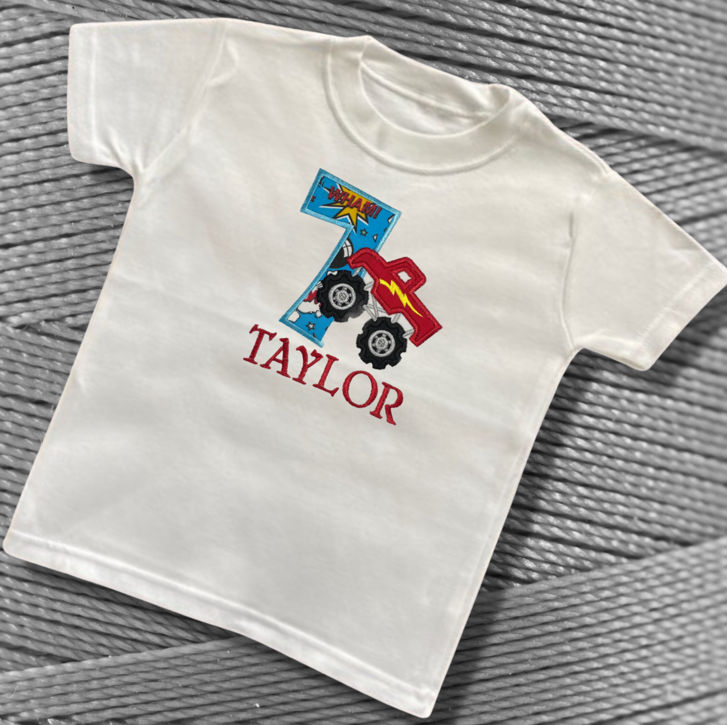 Childrens white soft cotton t-shirt. Embroidered applique on the front with the birthday age, monster truck design and the childs name.