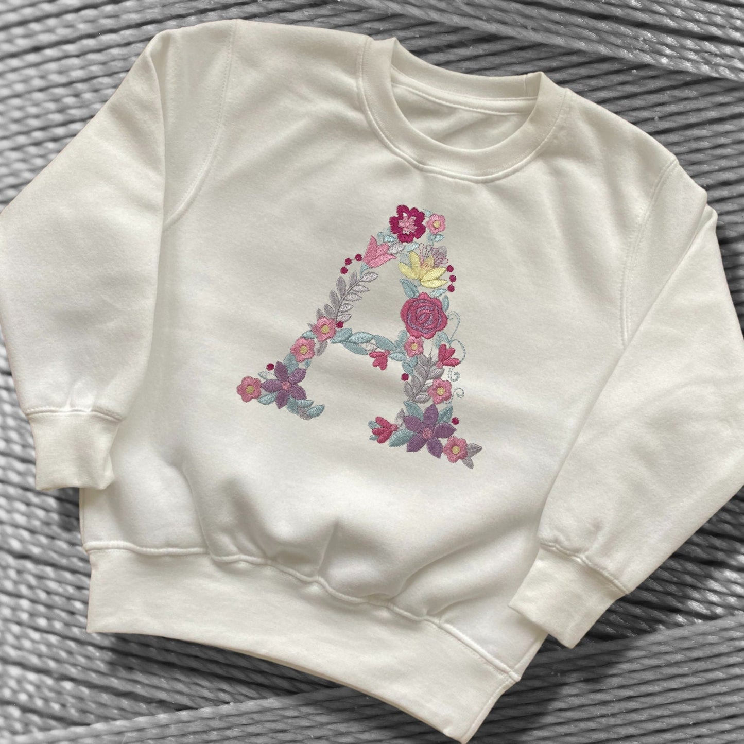 Personalised Embroidered Children's Monogram Top. Cute Floral Letter Embroidered in Pastel Pinks and Lilac.