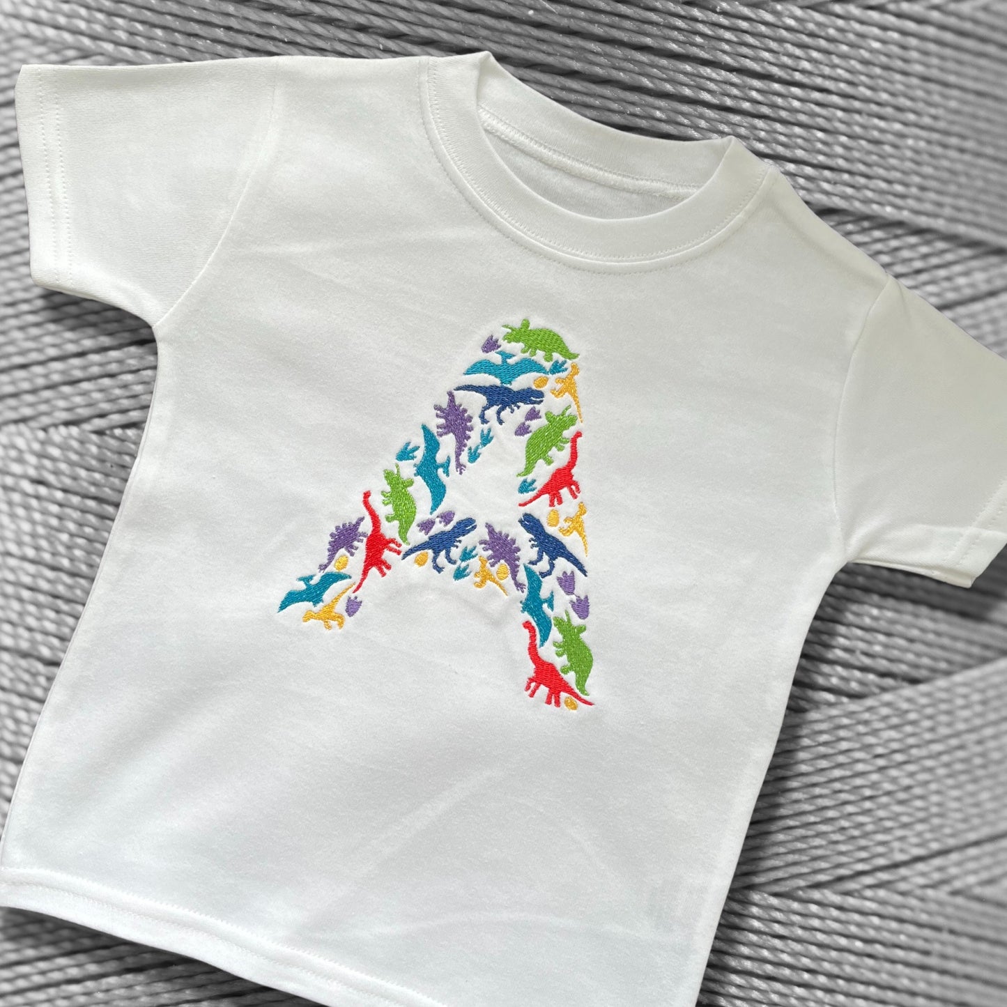 Personalised Embroidered Children's Dinosaur Top. Colourful Dinosaur's Make Up the Letter of the Alphabet. A Perfect Gift for Dinosaur Fans.