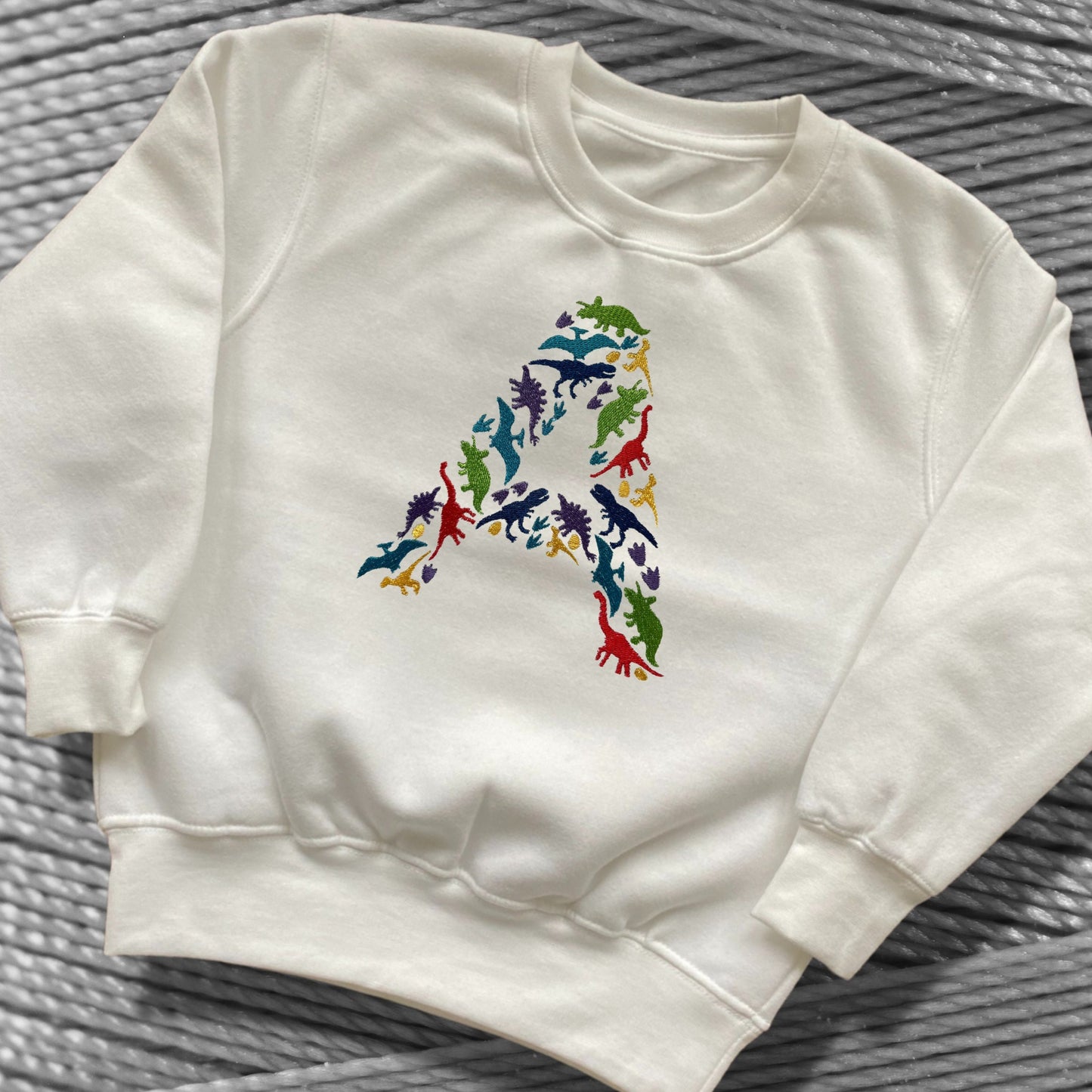 Personalised Embroidered Children's Dinosaur Top. Colourful Dinosaur's Make Up the Letter of the Alphabet. A Perfect Gift for Dinosaur Fans.