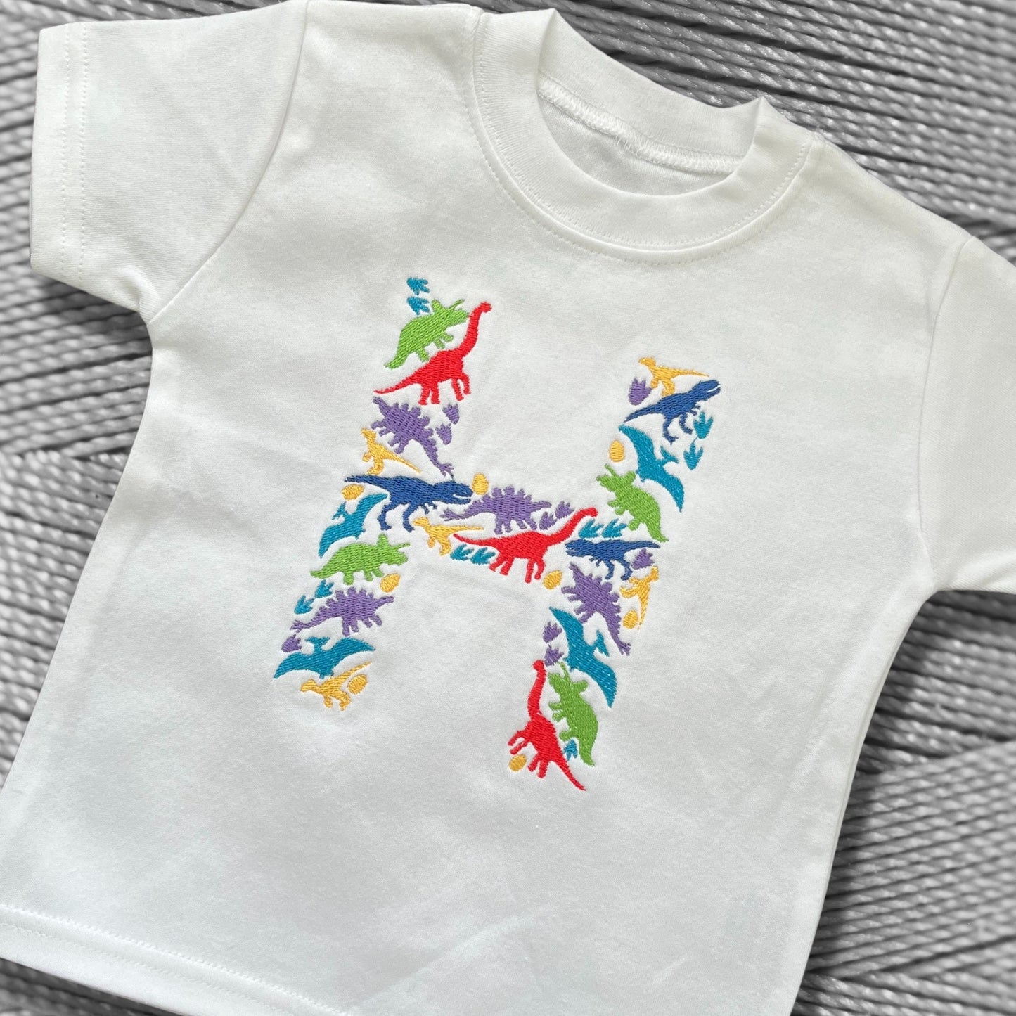 Personalised Embroidered Children's Dinosaur Top. Colourful Dinosaur's Make Up the Letter of the Alphabet. A Perfect Gift for Dinosaur Fans.