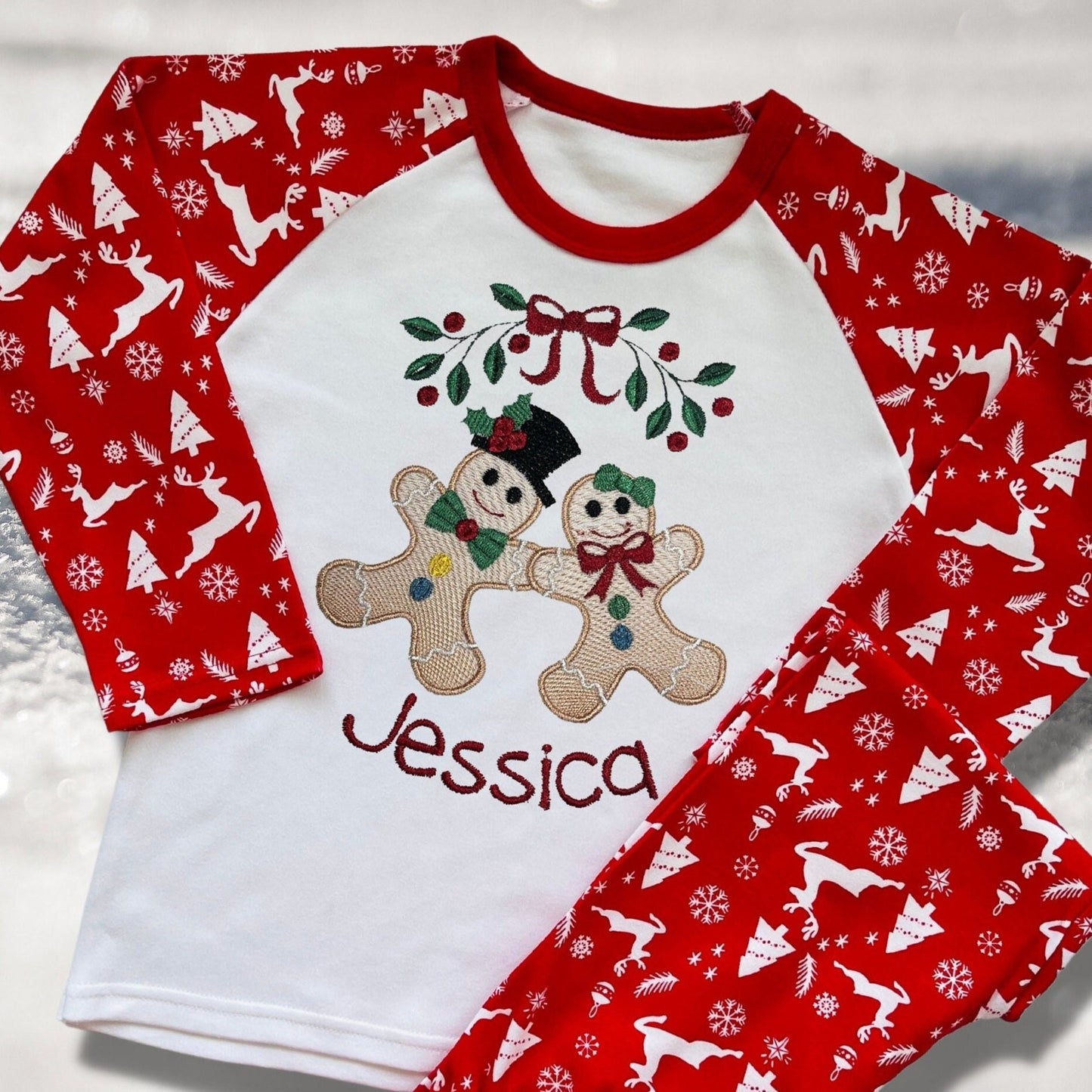 Personalised Embroidered Christmas Childrens Pyjamas and Rompersuits with the Cutest Gingerbread Girl and Boy Holding Hands Under a Garland.