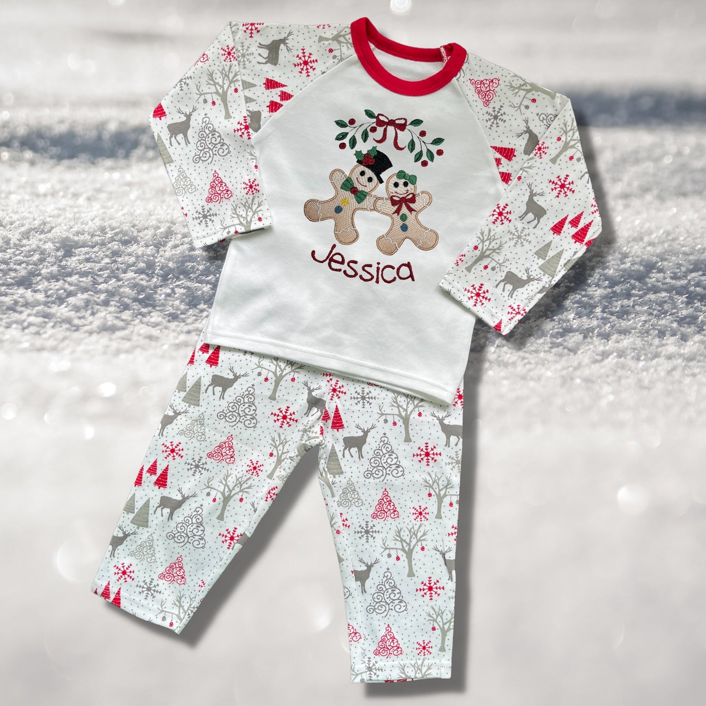 Personalised Embroidered Christmas Childrens Pyjamas and Rompersuits with the Cutest Gingerbread Girl and Boy Holding Hands Under a Garland.
