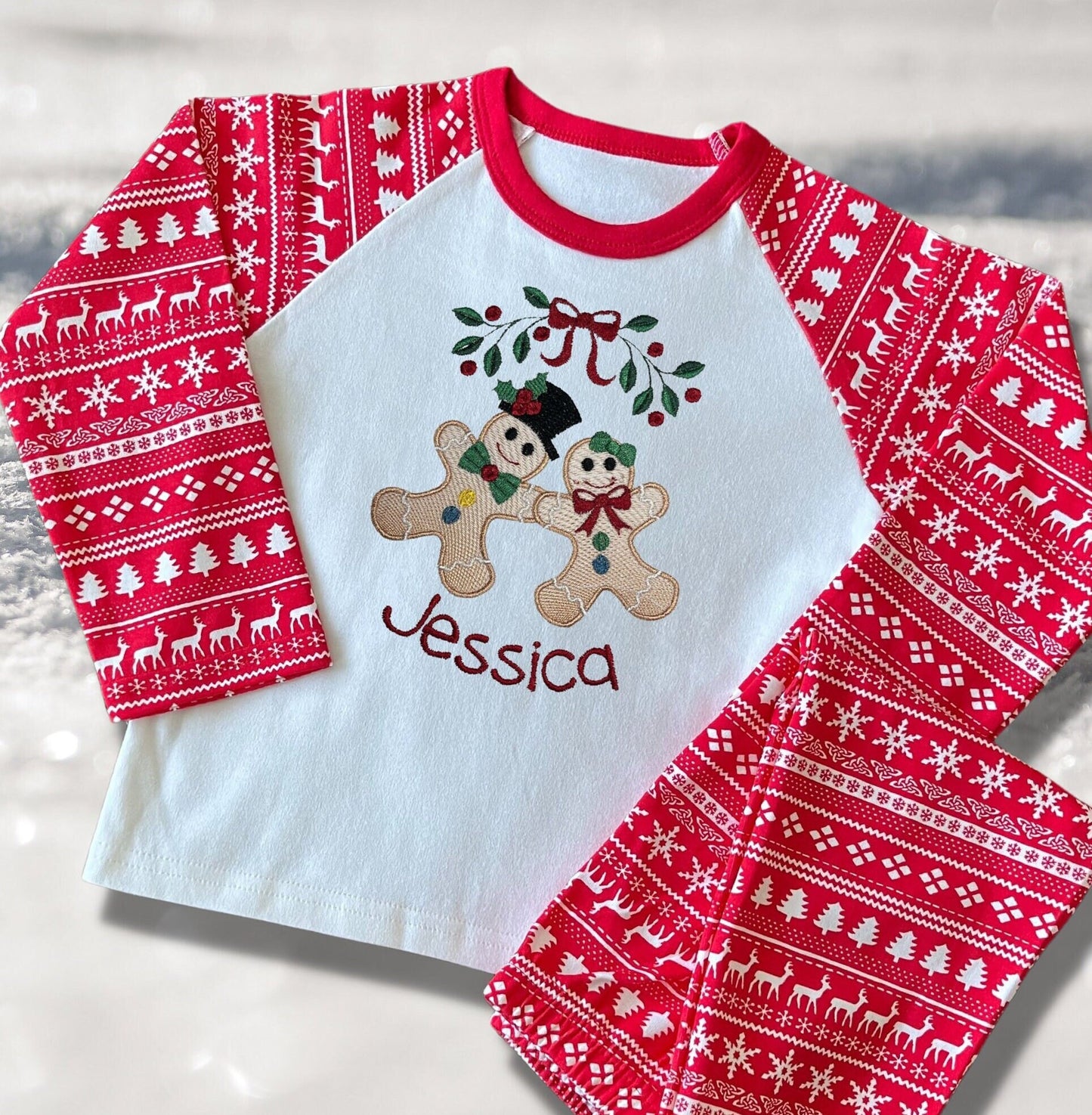 Personalised Embroidered Christmas Childrens Pyjamas and Rompersuits with the Cutest Gingerbread Girl and Boy Holding Hands Under a Garland.