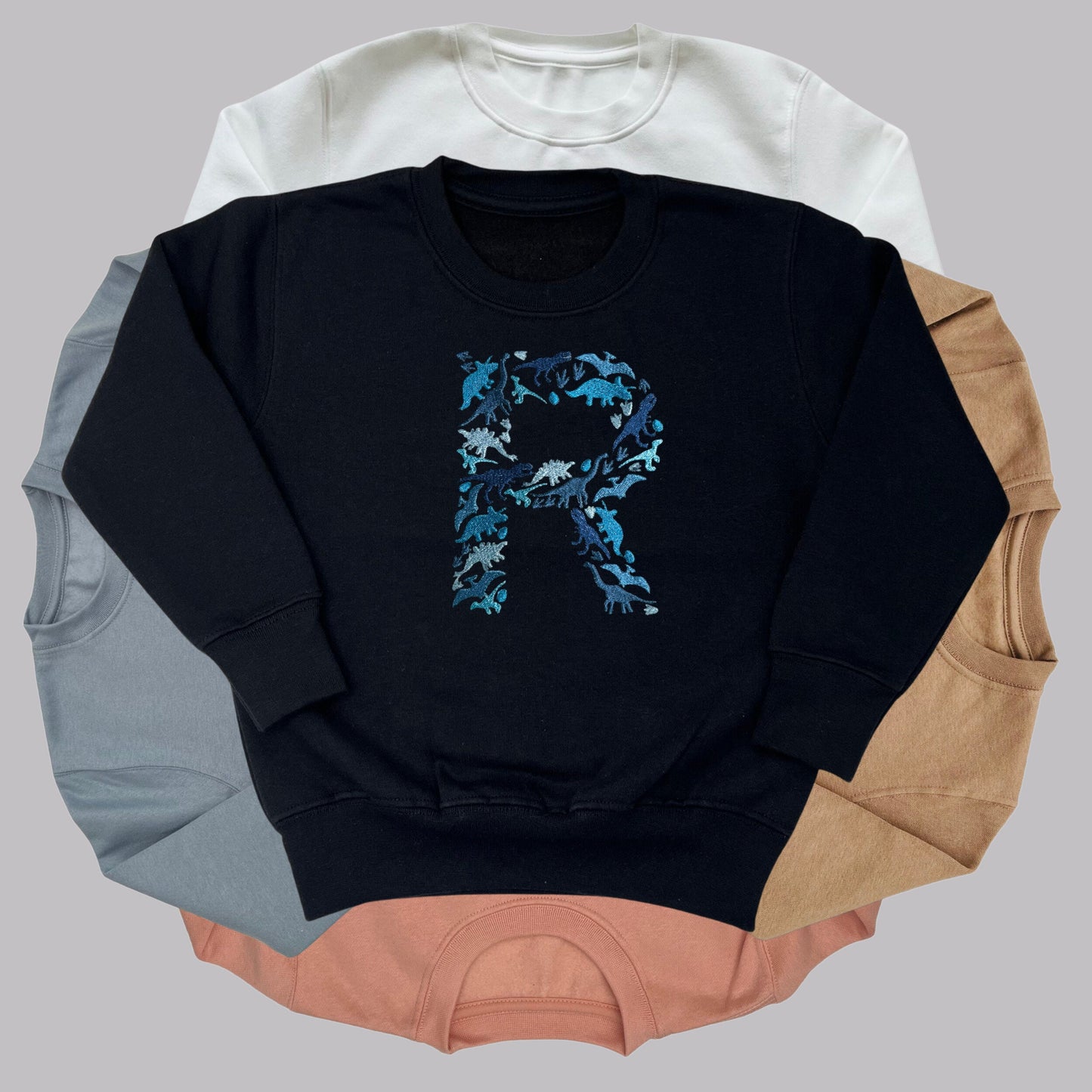 Personalised Embroidered Childrens Dinosaur Top. Dinosaurs in Beautiful Shades of Blue Make Up the Letter. A Perfect Gift for Dinosaur Fans.