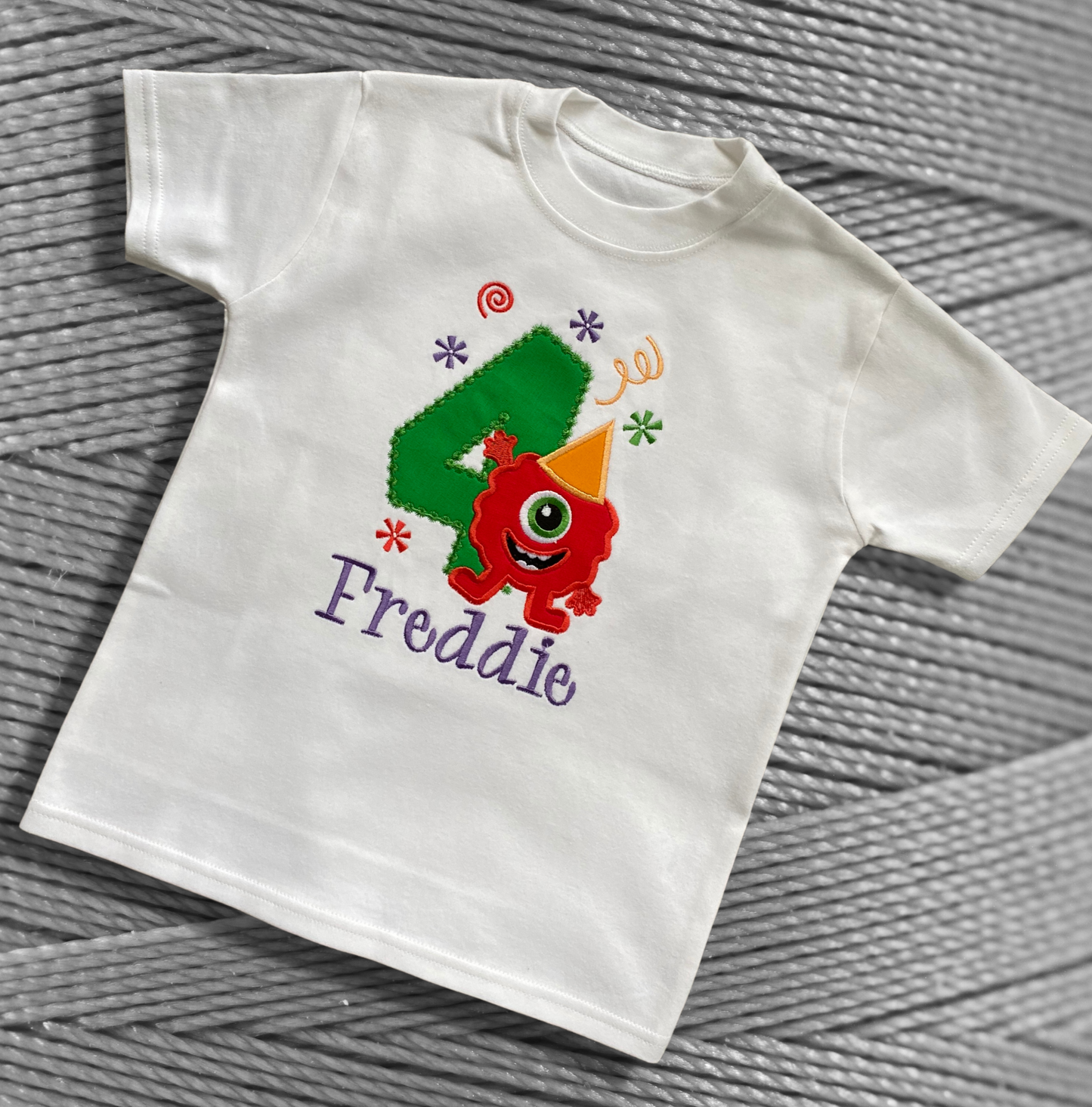 Childrens white soft cotton t-shirt. Embroidered applique on the front with the birthday age, funny monster design and the childs name.
