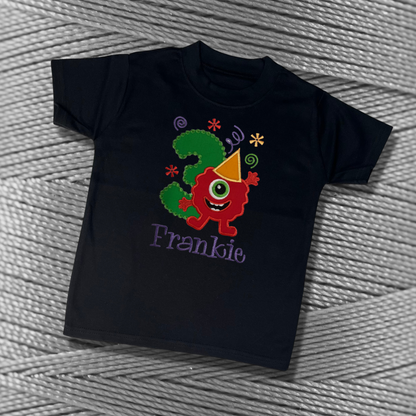 Childrens black soft cotton t-shirt. Embroidered applique on the front with the birthday age, funny monster design and the childs name.