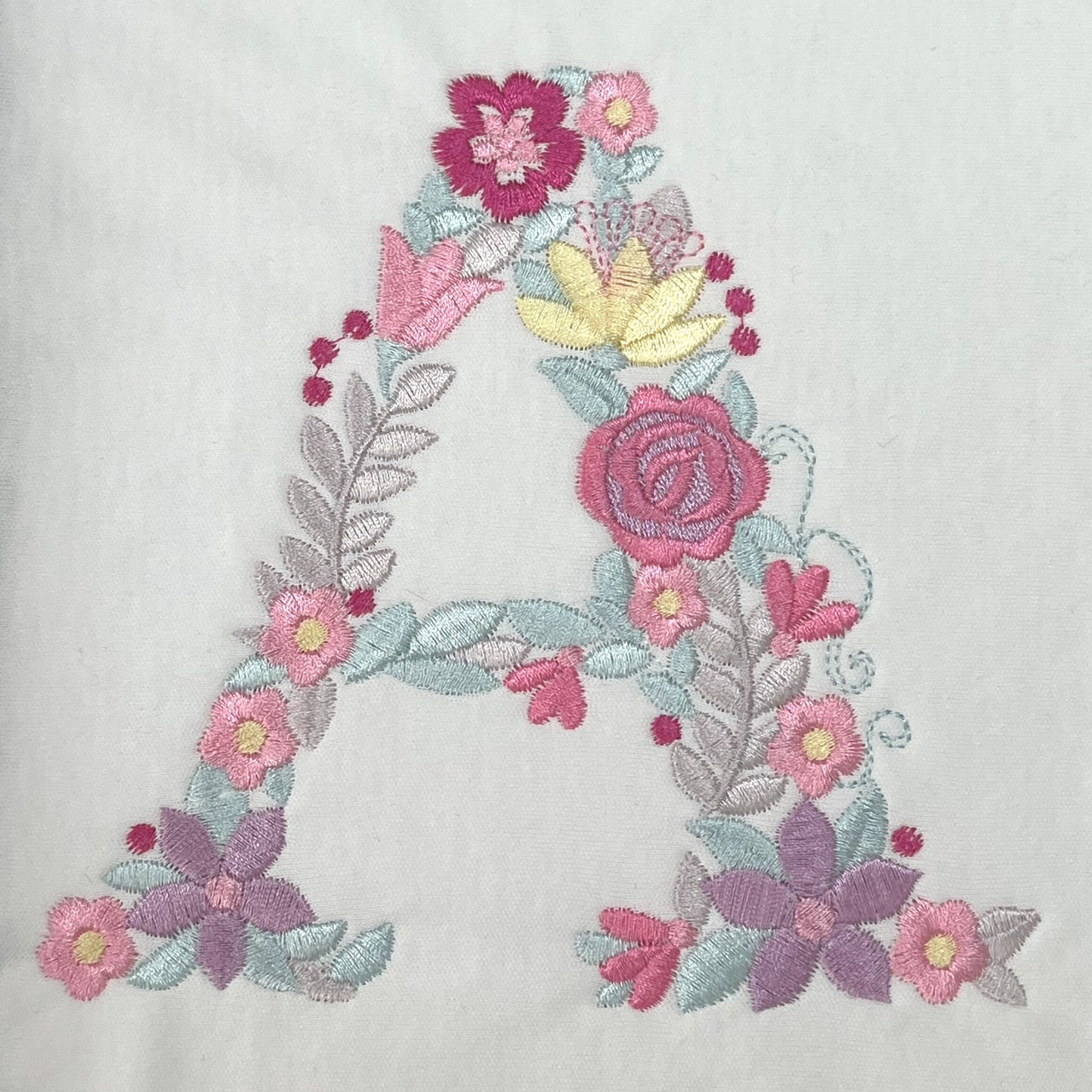 Personalised Embroidered Children's Monogram Top. Cute Floral Letter Embroidered in Pastel Pinks and Lilac.