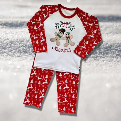 Personalised Embroidered Christmas Childrens Pyjamas and Rompersuits with the Cutest Gingerbread Girl and Boy Holding Hands Under a Garland.