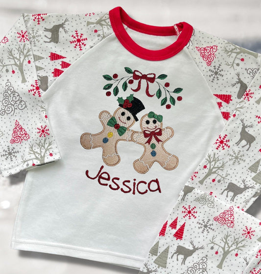 Personalised Embroidered Christmas Childrens Pyjamas and Rompersuits with the Cutest Gingerbread Girl and Boy Holding Hands Under a Garland.