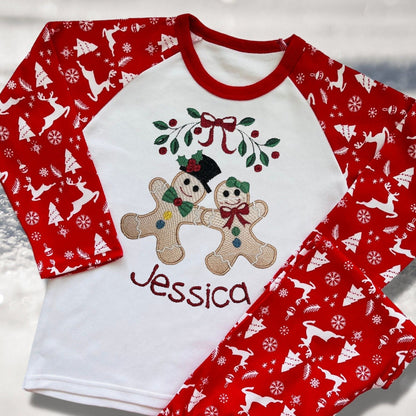 Personalised Embroidered Christmas Childrens Pyjamas and Rompersuits with the Cutest Gingerbread Girl and Boy Holding Hands Under a Garland.