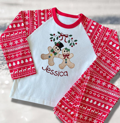 Personalised Embroidered Christmas Childrens Pyjamas and Rompersuits with the Cutest Gingerbread Girl and Boy Holding Hands Under a Garland.