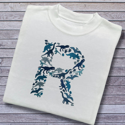 Personalised Embroidered Childrens Dinosaur Top. Dinosaurs in Beautiful Shades of Blue Make Up the Letter. A Perfect Gift for Dinosaur Fans.