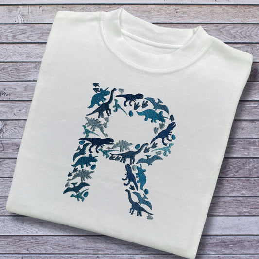 Personalised Embroidered Childrens Dinosaur Top. Dinosaurs in Beautiful Shades of Blue Make Up the Letter. A Perfect Gift for Dinosaur Fans.